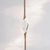 Light bronze sculptural lamp with flared stem and large, clear glass element against pale pink to gray gradient backdrop.